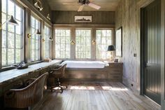 a bedroom with wood floors and large windows, along with a bed in the corner