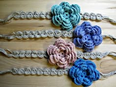 three crocheted flower headbands on top of a wooden table