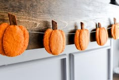 pumpkins are hung on the clothes line in front of a wooden board with pegs