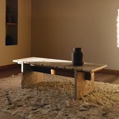 a wooden table sitting on top of a shaggy rug next to a candle and window