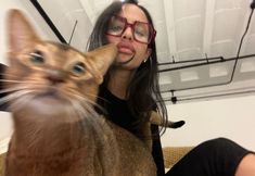 a woman holding a cat up to her face and making a funny face at the camera