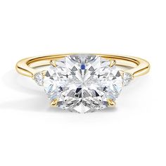 a three stone engagement ring with an oval cut diamond in the center