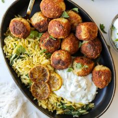 a black bowl filled with pasta and meatballs on top of a white tablecloth