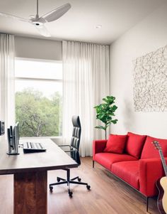 a living room with red couches and a guitar on the table in front of a window