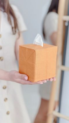 a woman holding a tissue box in her hand