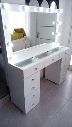 a large white vanity with lights on it's sides and drawers in front of a mirror