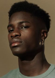 a young man with black hair and gold earrings