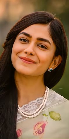 a close up of a person wearing a necklace and smiling at the camera with long hair