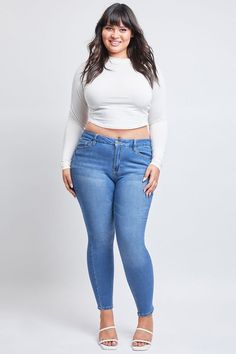 a woman in high rise jeans and white top posing for the camera with her hands on her hips