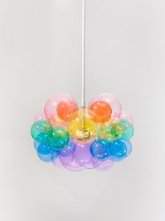 a multicolored bird feeder hanging from a white ceiling with balloons attached to it