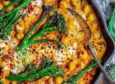 a skillet filled with pasta and broccoli covered in white sauce on top of a wooden table