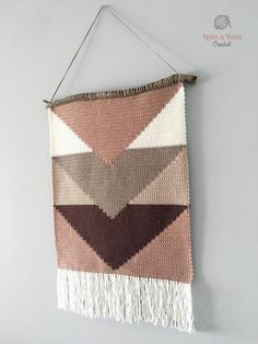 a woven wall hanging with tassels on it