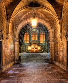 an archway leading into a building with stone walls and arched doorways that lead to the second floor