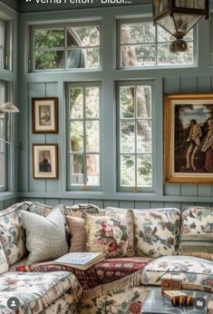 a living room filled with furniture and windows next to a painting hanging on the wall