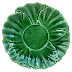 a green ceramic dish with large leaves on the top and bottom, sitting in front of a white background