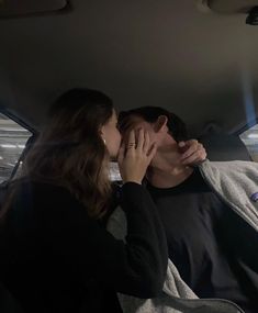 a man and woman kissing in the back seat of a car with their eyes closed