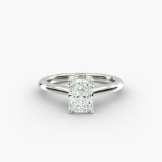 a cushion cut diamond engagement ring on a white background, with the center stone set in 18k white gold