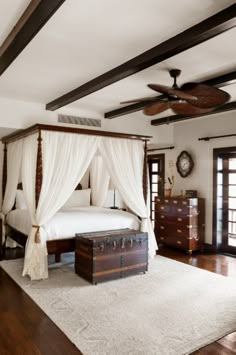 a bedroom with a canopy bed and white drapes