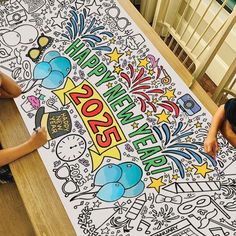 two children sitting at a table with a large poster on it that says happy new year