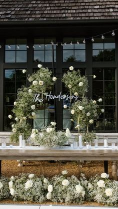 a table with white flowers and candles on it in front of a storefront window