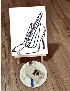 a drawing of a high heeled shoe on top of a table next to a plate