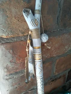 a white and gold decorated toothbrush holder hanging from a brick wall with feathers on it