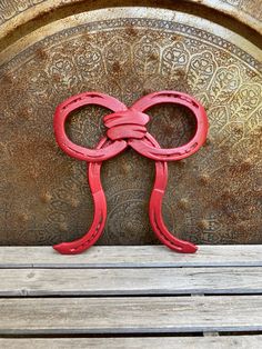 a pair of red scissors sitting on top of a wooden bench