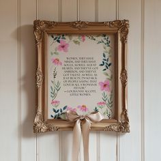 an ornate frame with a quote on it and a bow hanging from the wall next to it