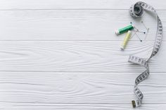 measuring tape, scissors and thread on white wooden background