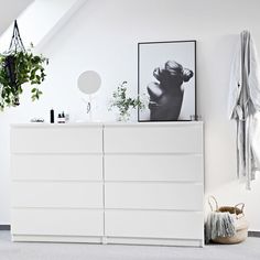 a white dresser sitting next to a potted plant