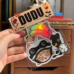 a person holding up a sticker with the word dudu in front of it