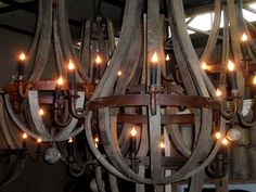 a chandelier made out of wooden barrels with lights hanging from the top and bottom