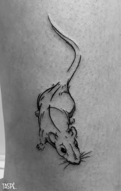 a small rat tattoo on the back of a woman's leg, it is black and white