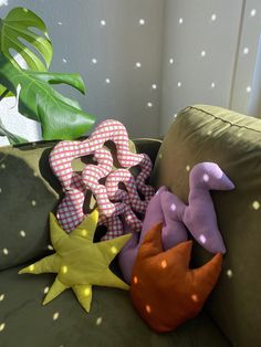 three stuffed animals sitting on top of a green couch next to a potted plant