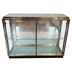 an empty glass display case with gold trimmings on the doors and bottom shelves