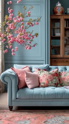 a living room with blue walls and pink flowers on the couch