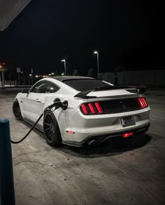 a white mustang parked in a parking lot at night