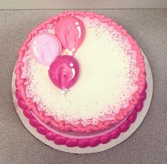 a birthday cake with pink and white frosting, balloons in the shape of hearts