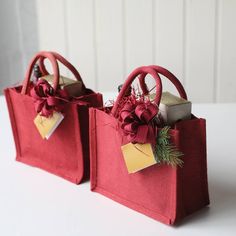 two red bags with bows and tags on them sitting next to each other in front of a white wall