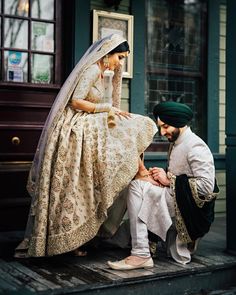 a man kneeling down next to a woman in a white dress and green turban