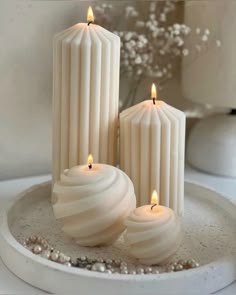 three white candles sitting on top of a plate