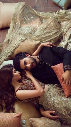 a man and woman laying on top of a bed next to each other with pillows