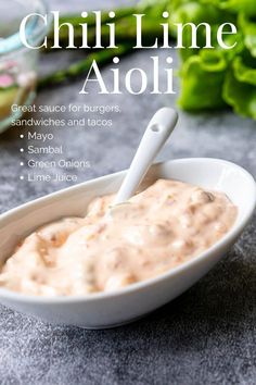 a white bowl filled with sauce next to lettuce and other vegetables on the table