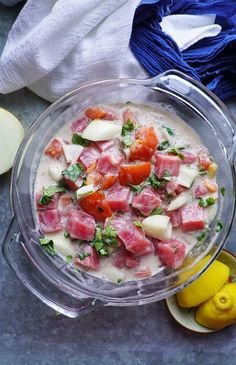 a bowl filled with food next to sliced lemons and an apple on the side