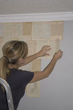 a woman is leaning against the wall with her arms stretched out and reading a book