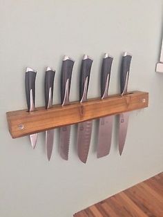 there are many knives hanging on the wall with each one's own knife holder