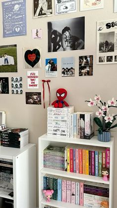 a white book shelf filled with lots of books next to a wall covered in pictures