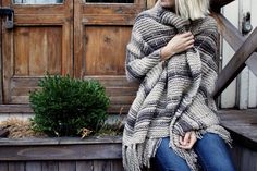 a woman is sitting on the steps wearing a sweater and jeans with her arms wrapped around her shoulders