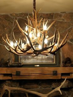 a deer antler chandelier hanging from the ceiling in front of a fireplace