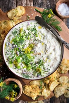 a bowl of dip surrounded by crackers and herbs